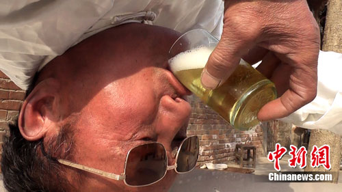 河南66歲老人倒立寫字喝酒遠近聞名