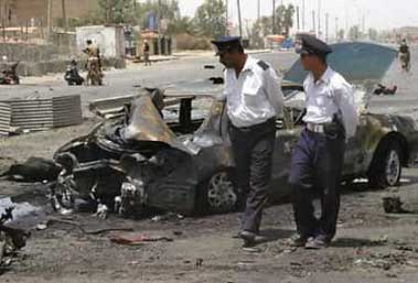Iraqi policemen view a destroyed vehicle after a car bomb attack on an Iraqi army convoy killed six people and wounded 15 in Baghdad July 15, 2005.