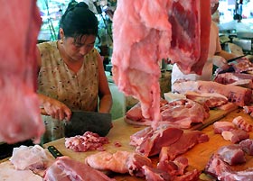A vendor prepares pork at a market in Shanghai yesterday. China�K�s far south is on high alert since one person was killed and three infected by a pig-borne disease that had left nearly 40 dead in the southwest. The latest person killed by the disease, caused by the Streptococcus suis bacterium, had handled infected pork, Xinhua news agency said on Tuesday. The three other victims, all butchers, also likely had contact with infected meat. 
