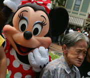 An elderly woman poses with Minnie Mouse at Hong Kong Disneyland September 12, 2005.