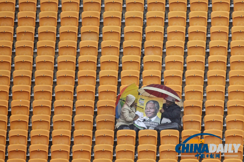 曼德拉追悼會現(xiàn)場:情侶為偉人海報(bào)打傘