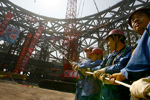 A worker cycles pass the site of the National Stadium, dubbed the