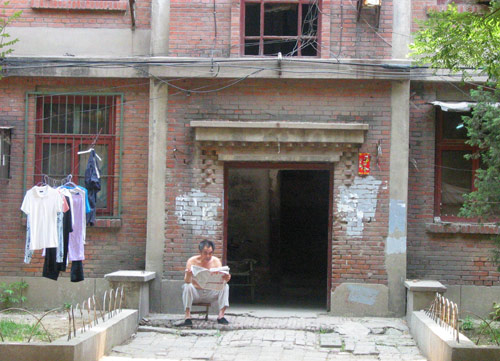 A Chinese man reads newspaper in Juixiaqiao Sub-district in Beijing, June 9, 2007. Local government in Jiuxianqiao and the real estate developer jointly organize the vote on Saturday to see if majority residents of over 5000 families accept the new compensation policy after failed attempts to reach an agreement through other ways. Both notary officials and supervisors are invited to monitor the vote that runs from 9 a.m. to 9 p.m. at six ballot booths. [Sun Yuqing/m.szjzcy.com]