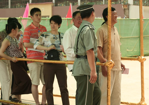 A security man talks with residents at the venue for a vote on demolishment and reconstruction of old buildings in Juixiaqiao Sub-district in Beijing, June 9, 2007. Local government and the real estate developer jointly organize the vote on Saturday to see if majority residents of over 5000 families accept the new compensation policy after failed attempts to reach an agreement through other ways. Both notary officials and supervisors are invited to monitor the vote that runs from 9 a.m. to 9 p.m. at six ballot booths. [Sun Yuqing/m.szjzcy.com]