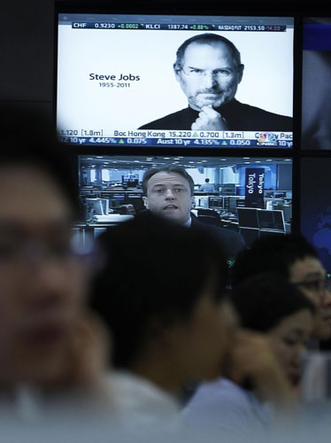 A monitor shows the obituary of former Apple CEO Steve Jobs as foreign currency dealers of the Korea Exchange Bank work at the bank's dealing room in Seoul October 6, 2011. The world mourns Steve Jobs