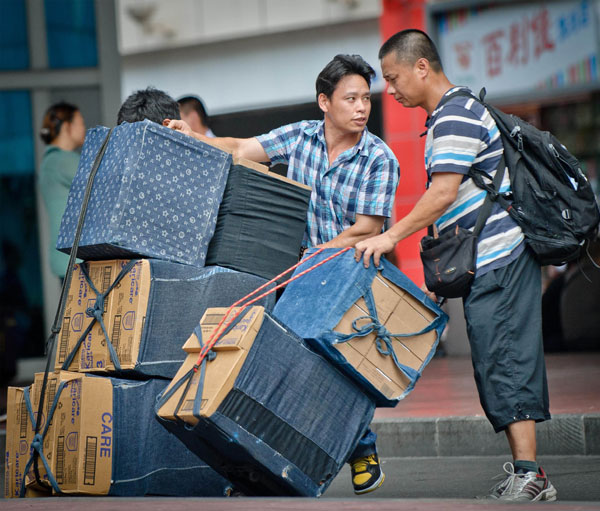 Two men take care of boxes containing foreign milk powder products brought from Hong Kong outside the Luohu Port in Shenzhen, Guangdong province, on May 24. Liu Dawei / Xinhua Foreign milk powder still pricey