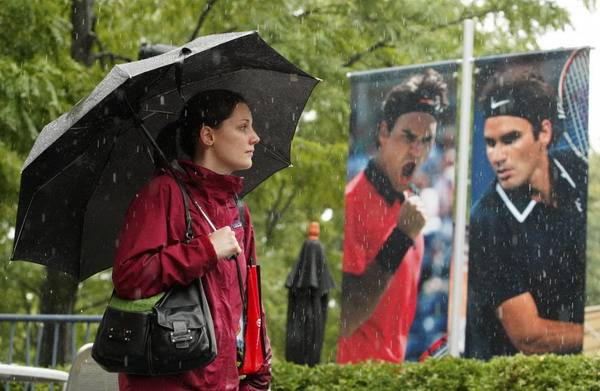 A patron walks under an umbrella after rain postponed matches at the US Open tennis tournament in New York, Sept 6, 2011. Foul weather sets up late schedule at US Open