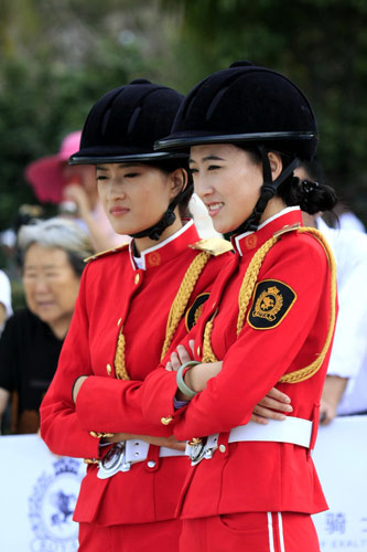 Women in European-style outfits look on during a beach equestrian festival, March 28, 2013. Beach equestrian festival held in S China