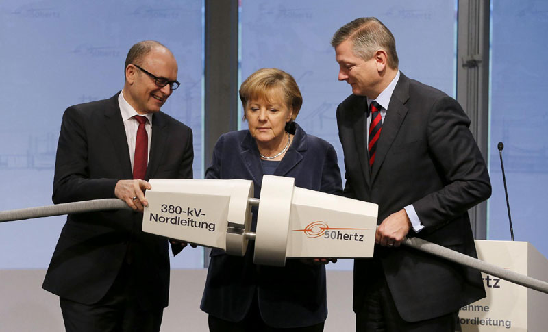 (L-R) Prime Minister of Mecklenburg-Vorpommern Erwin Sellering, German Chancellor Angela Merkel and 50Hertz Transmission Company CEO Boris Schucht commemorate the new 380-kV high voltage power line between Schwerin and Hamburg by plugging in a giant mock cable, in Schwerin, Dec 18, 2012. Images of the day - Dec 18
